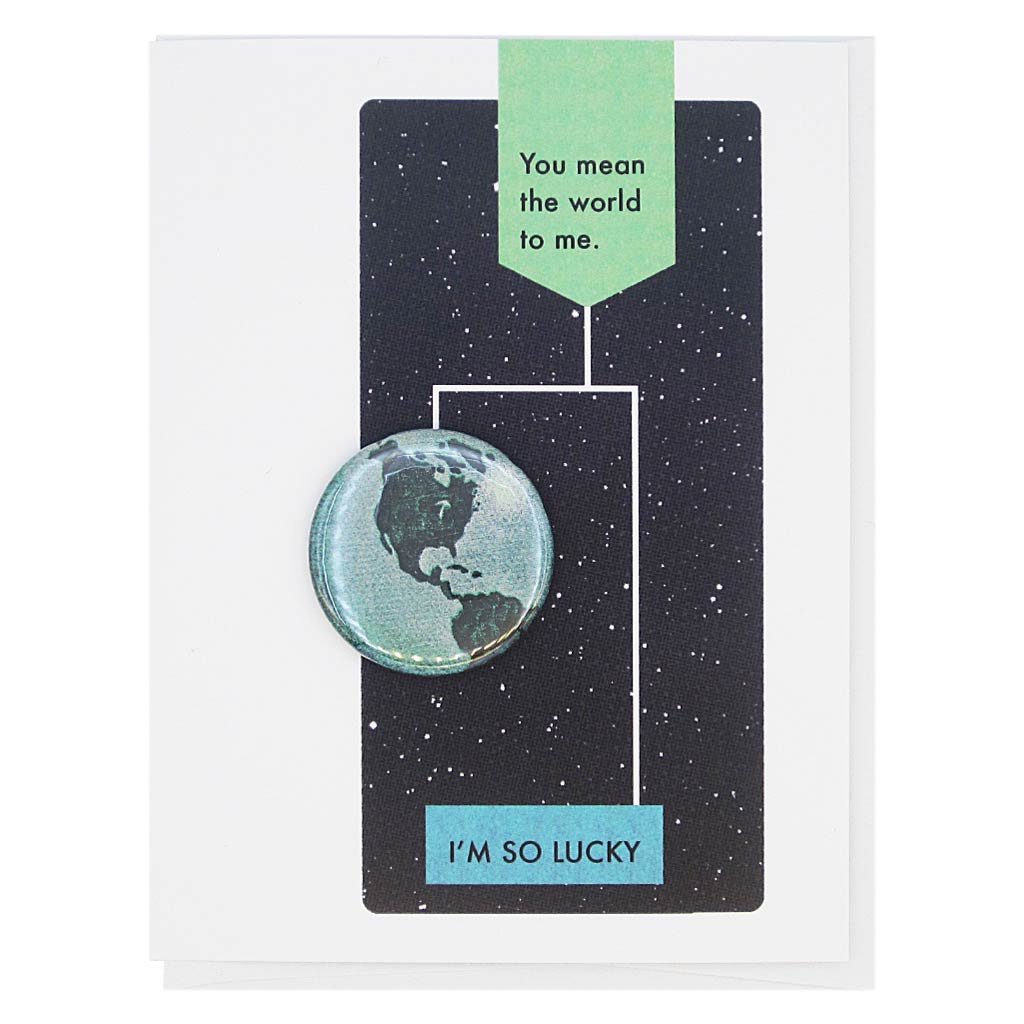 This card is designed to look like a page from a vintage science textbook with a black background of a starry sky. The text reads, ‘You Mean the World to Me’ with an arrow to the text ‘I’m so Lucky’ with an arrow to a 1¼” button of the earth that can be taken off and worn by the recipient. Card measures 4¼” x 5½”, comes with a white envelope & is blank inside. Designed by The Regional Assembly of Text.