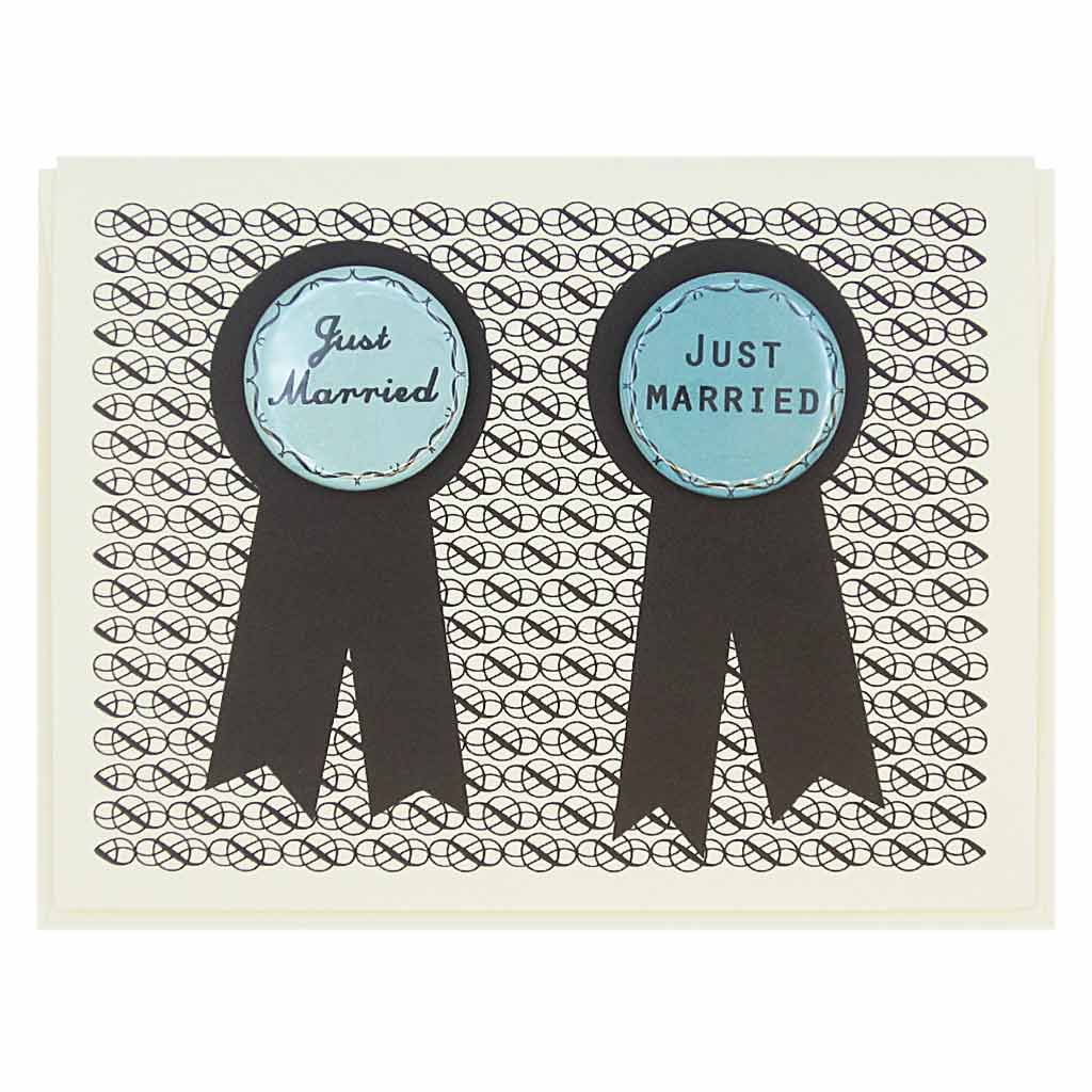 This card has two prize ribbons side by sided and features two 1¼” buttons that say ‘Just Married’ that can be taken off and worn by the recipients. Let us know during checkout if you need 2 new grandmas or 2 new grandpas instead. Card measures 4¼” x 5½”, comes with a cream envelope & is blank inside. Designed by The Regional Assembly of Text.