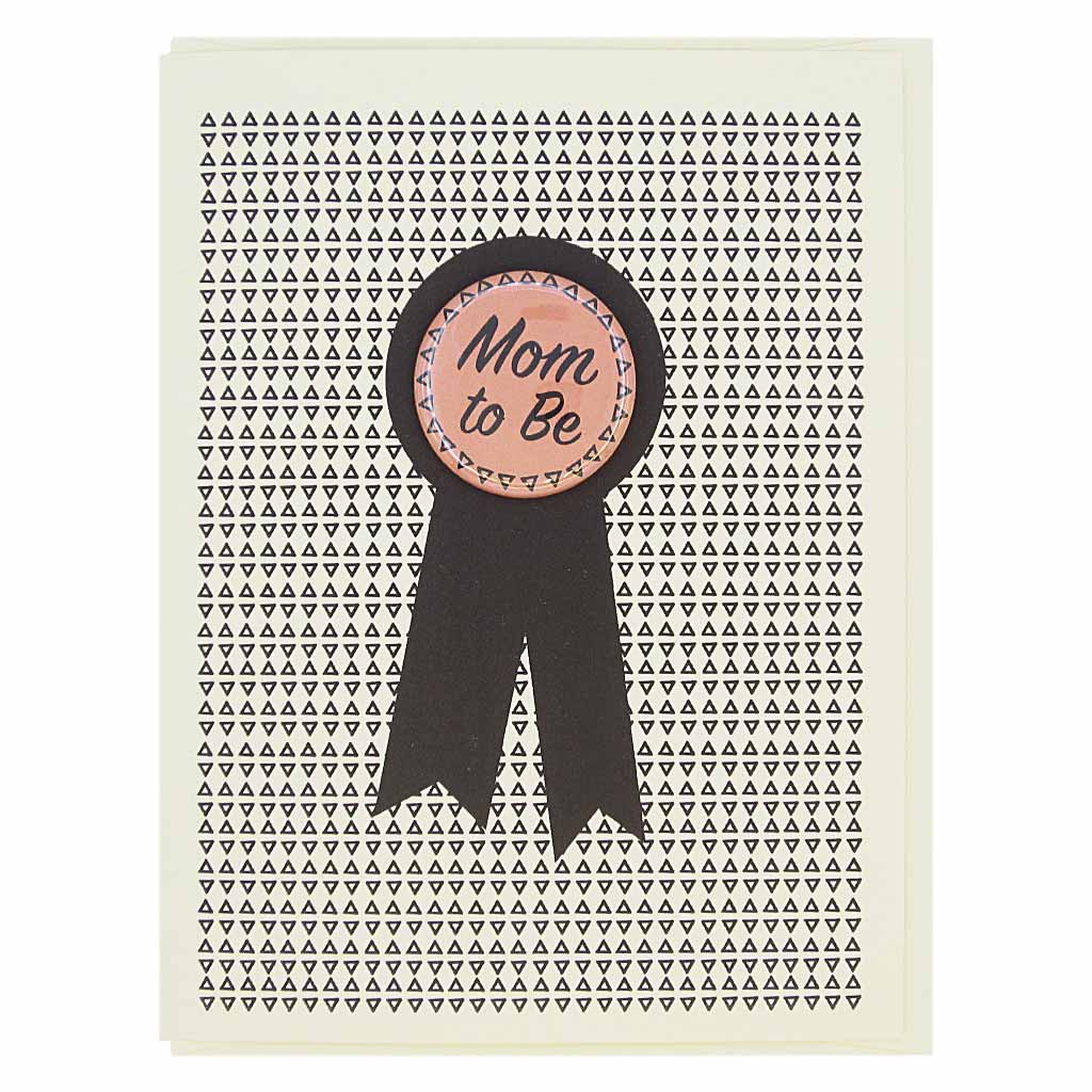 This card looks like a prize ribbon. Features a 1½” button with the text ‘Mom to Be’ that can be taken off and proudly worn by the recipient. Card measures 4¼” x 5½”, comes with a cream envelope & is blank inside. Designed by The Regional Assembly of Text.