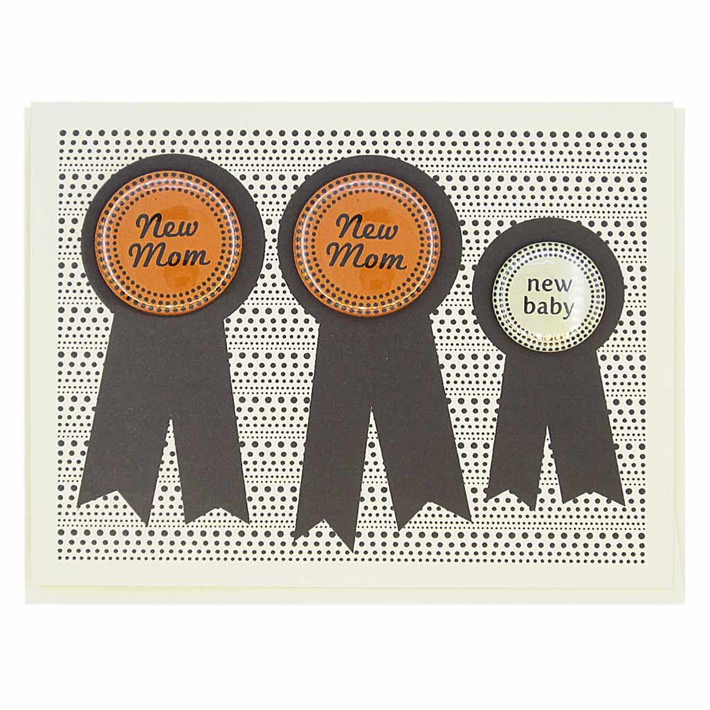 This card has three prize ribbons side by sided and features 3 buttons that can be taken off and worn by the recipients. Two say ‘New Mom’ and the other smaller button says ‘New Baby’. Perfect for the new family. Card measures 4¼” x 5½”, comes with a cream envelope & is blank inside. Designed by The Regional Assembly of Text.