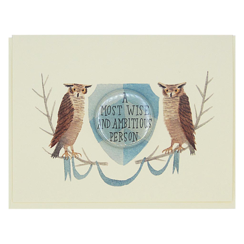 This lovely card features a watercolour painting of two owls on either side of a crest. There is a 1½” button in the middle of the crest which reads ‘a most wise and ambitious person’. The button can be taken off and worn by the recipient. Card measures 4¼” x 5½”, comes with a cream envelope & is blank inside. Designed by The Regional Assembly of Text.