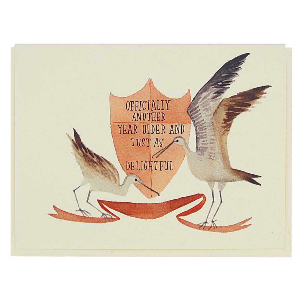 This beautiful and birthday card features a watercolour painting of sandpipers surrounding a crest which reads ‘officially another year older and just as delightful’ Card measures 4¼” x 5½”, comes with a cream envelope & is blank inside.Designed by The Regional Assembly of Text.